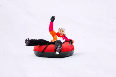 girl tubing down a snowy hill