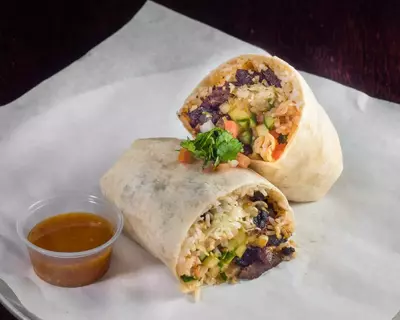 Burrito cut in half with cup of salsa