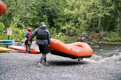 people carry a raft to a river