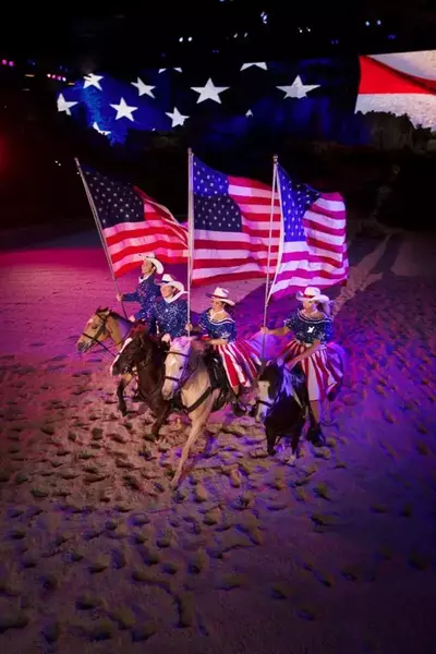 horse riders carrying flags from dolly's stampede