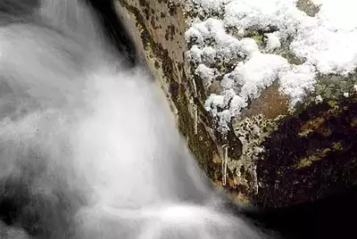 snowy rock next to water