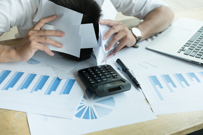 stressed man crunching numbers and viewing reports