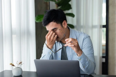 man with his head in his hand at his laptop