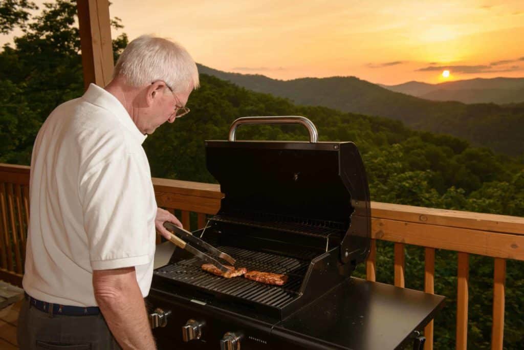 old man grilling on the deck of a smoky mountain cabin