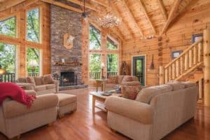 pigeon forge cabin living room with light tan couches and stone fireplace